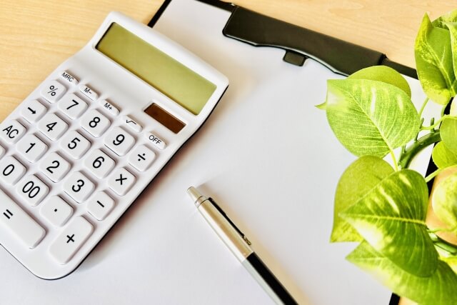 電卓とクリップボードと観葉植物